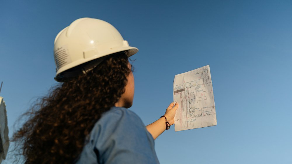A site manager in a hard hat reviewing plans